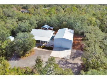 A bird's eye view of a charming house with a light-colored roof, a spacious garage, and a lush green surrounding at 4525 Owls Nest Ct, De Leon Springs, FL 32130