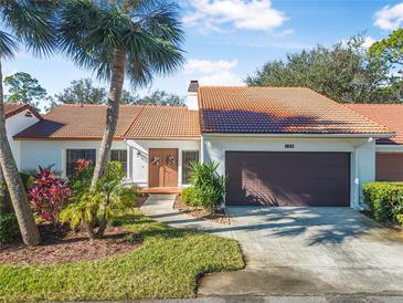 Front view of charming villa with brown garage door and lush landscaping at 129 Oyster Catcher Ct, Daytona Beach, FL 32119