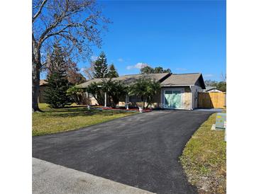 Ranch-style home with a paved driveway and landscaped lawn at 213 Lone Pine Dr, Edgewater, FL 32132