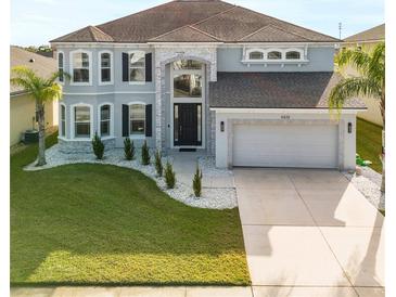 Two-story house with gray exterior, stone accents, and a three-car garage at 6832 Forkmead Ln, Port Orange, FL 32128