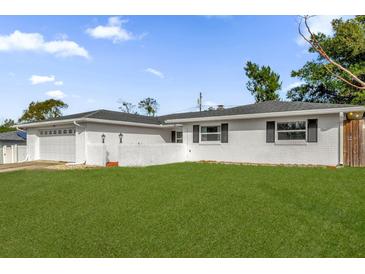 Charming white brick home with a well-manicured lawn and an attached two-car garage at 728 Vicksburg St, Deltona, FL 32725