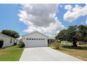 White house with attached garage and landscaped yard at 935 Chula Ct, The Villages, FL 32159