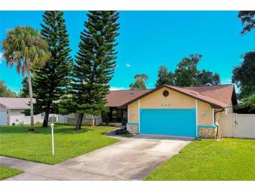 Charming home with vibrant blue garage door and stone accents, complemented by mature trees and well-manicured lawn at 949 Tall Pine Dr, Port Orange, FL 32127