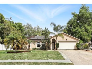 Charming single-story home with a two-car garage, beautiful landscaping, and mature palm trees under a sunny sky at 583 Wilburton Dr, Deltona, FL 32738