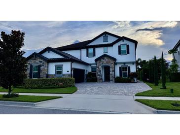 Charming two-story home featuring stone accents, a paved driveway, manicured landscaping, and a dark-colored roof at 6301 Swanson St, Windermere, FL 34786