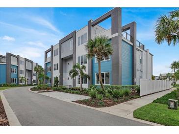 Beautiful modern condo building with lush landscaping and a blue and gray color scheme at 7740 Sandy Ridge Dr # 206, Kissimmee, FL 34747