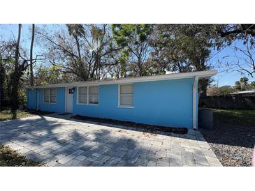 Blue house with a gray brick driveway, white trim, and mature trees at 102 Judges Ln, Port Orange, FL 32129