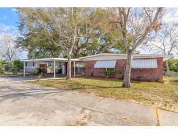 Charming single-story red brick home featuring a covered carport and well-maintained front yard at 1117 Berkshire Rd, Daytona Beach, FL 32117