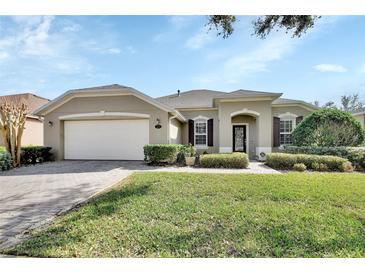 Charming one-story home features a manicured lawn and a brick driveway leading to a two-car garage at 205 Victoria Trails Blvd, Deland, FL 32724