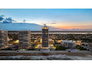 Stunning aerial view of beachfront condos, showcasing ocean and city views at twilight at 3000 N Atlantic Ave # 24, Daytona Beach, FL 32118