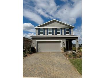 Charming two-story home with a gray exterior, blue shutters, landscaped yard, and brick driveway at 7024 Lanier Falls Rd, Deland, FL 32724