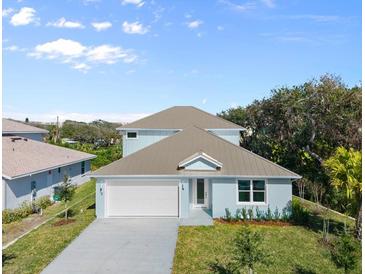 Charming single-Gathering home featuring a light-blue exterior, well-manicured lawn, and an attached two-car garage at 72 Aurora Ave, Ponce Inlet, FL 32127