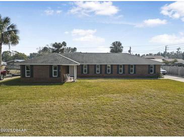 Charming brick ranch-style home with a well-maintained lawn at 825 Wells Dr, South Daytona, FL 32119