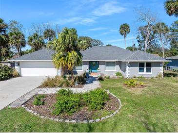 Charming single-story home with a well-manicured lawn and a beautiful garden in front at 13 Sandcastle Dr, Ormond Beach, FL 32176