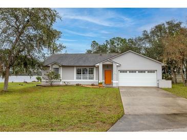 Charming home featuring a well-manicured lawn, attached garage, and freshly painted exterior at 1983 Stacey Cir, Deltona, FL 32738