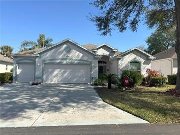 Charming single-story home with a well-manicured lawn, two-car garage, and lovely landscaping under a clear blue sky at 2327 Addison Ave, Clermont, FL 34711
