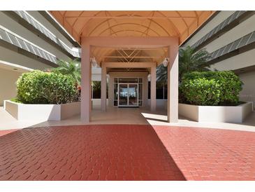 Inviting condominium entrance with covered entryway and red brick drive, framed by lush greenery at 2967 S Atlantic Ave # 1203, Daytona Beach Shores, FL 32118