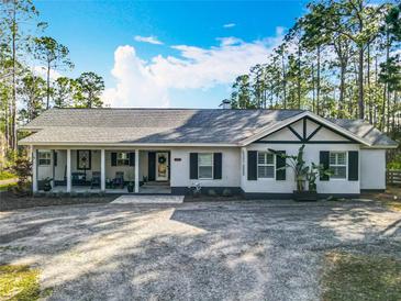 Charming single-story home featuring a covered porch, black shutters, neutral stucco, and mature trees at 4252 Quail Ranch Rd, New Smyrna Beach, FL 32168