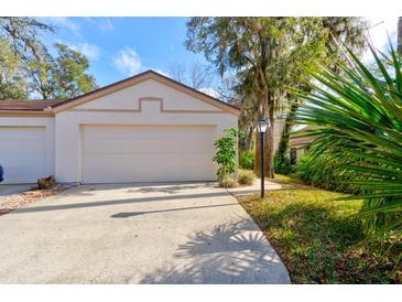 View of the home's garage and a paved driveway with landscaping and a lamp post at 6152 Sequoia Dr, Port Orange, FL 32127