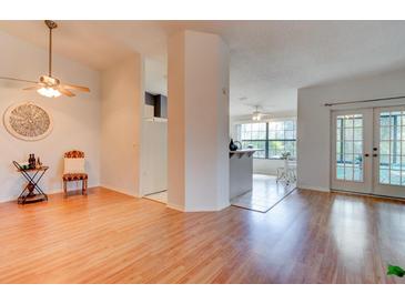 Bright living room with light wood floors, ceiling fan, and doorways to the kitchen and outdoor patio at 6152 Sequoia Dr, Port Orange, FL 32127