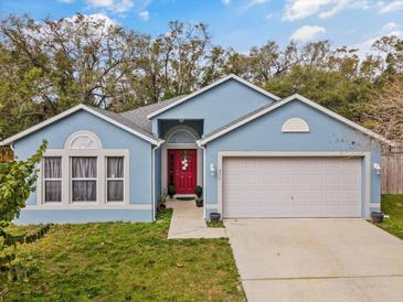 Charming single-story blue home with a red front door and attached two-car garage at 971 Cascades Park Trl, Deland, FL 32720