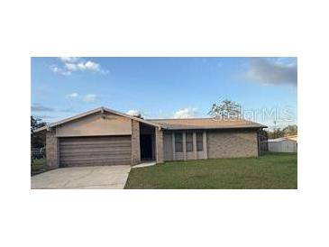 Single-story home featuring a large attached garage, brick facade, and manicured lawn at 1420 Felton St, Deltona, FL 32725