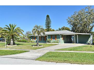 Charming single-story home with green paint, lovely shutters, carport, manicured lawn, and tropical landscaping at 1590 N Page Dr, Deltona, FL 32725