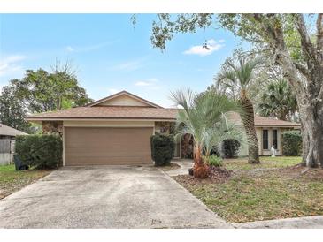 Charming single-story home featuring stone accents, a two-car garage, and mature landscaping at 1651 Kenlyn Dr, Longwood, FL 32779