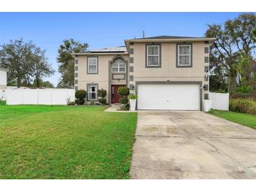 Two-story home featuring an attached two-car garage, a well-manicured lawn, and a neatly landscaped garden bed near the front entrance at 3318 Dewberry Dr, Deltona, FL 32738
