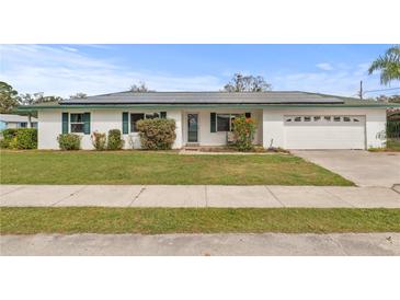Charming single-story home with a well-manicured lawn, walkway, and solar panels at 445 Virginia Ave, St Cloud, FL 34769