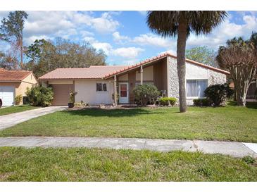 Charming single-story home featuring a well-manicured lawn and attractive exterior elevation with stone accents and terracotta-colored roof at 10477 Montpelier Cir, Orlando, FL 32821