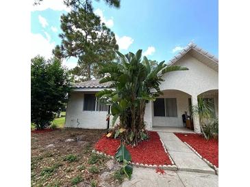 Charming single-story home with stucco exterior, mature landscaping, and a tiled roof under a bright blue sky at 3550 Forest Branch Dr # A, Port Orange, FL 32129