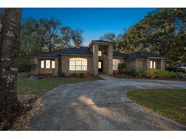 Charming brick home featuring a circular driveway and well-manicured landscaping at 1500 Wyngate Dr, Deland, FL 32724