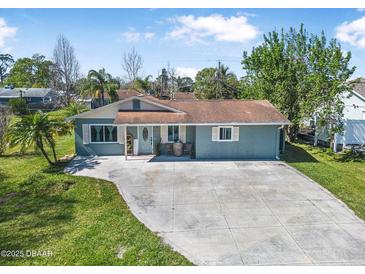 Charming single-story home with a well-maintained lawn and a spacious driveway at 2216 Umbrella Tree Dr, Edgewater, FL 32141
