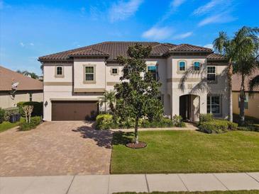 Stunning two-story home featuring lush landscaping, brick driveway, and a tile roof at 2344 Kelbrook Ct, Oviedo, FL 32765