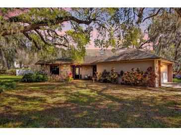 Charming single-story home featuring a stone facade and beautiful landscaping under a large, mature, shade tree at 4612 Reynosa Sw Dr, Winter Haven, FL 33880