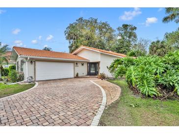 Charming single-story home with a red tile roof, brick driveway, and lush landscaping at 509 Osprey Ln, Winter Springs, FL 32708