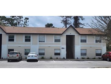 Exterior of a two-story condo building with neutral paint, brown roof, and ample parking at 411 Banana Cay Dr # C, South Daytona, FL 32119