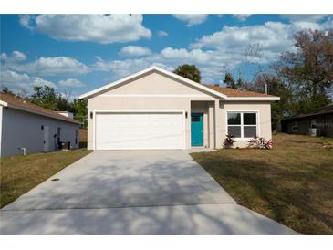 Charming single-story home featuring a two-car garage, a well-maintained lawn, and a bright blue front door at 951 Redwood St, Daytona Beach, FL 32117