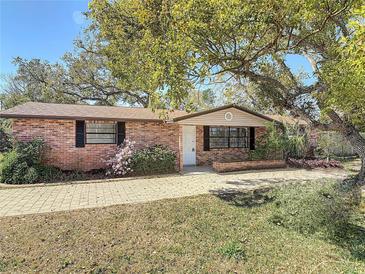Charming brick home with a well-maintained front yard, mature trees, and brick paved driveway at 1002 Charles St, Port Orange, FL 32129