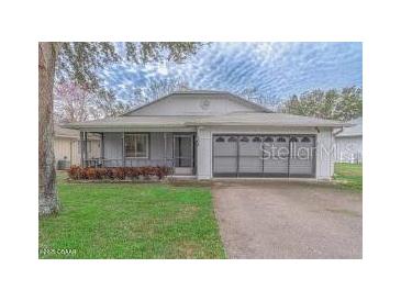 Charming single-story home with well-maintained lawn, screened porch and two-car garage at 102 Underbrush Trl, Port Orange, FL 32128