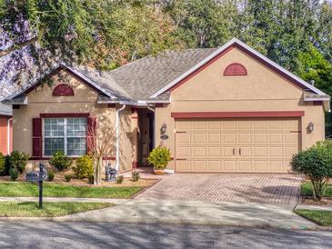 Charming one-story home with a well-manicured lawn, brick driveway, and a neutral-colored exterior at 107 Gladesdown Ct, Deland, FL 32724