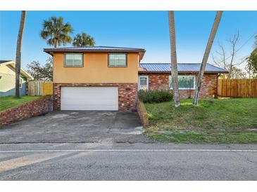Two-story home featuring a front yard, two-car garage, and a durable metal roof at 1493 Derbyshire Rd, Daytona Beach, FL 32117