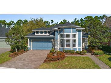 Charming blue two-story home with a two-car garage and professionally landscaped front yard and walkway at 376 Chelsea Place Ave, Ormond Beach, FL 32174