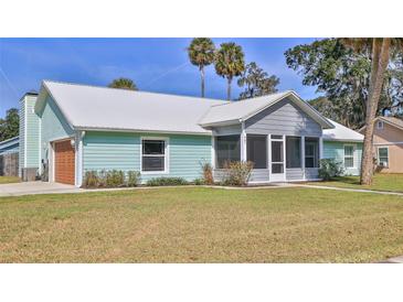 Charming single-story home features a metal roof, screened-in porch, garage and fresh green lawn at 437 Merrimac Dr, Port Orange, FL 32127