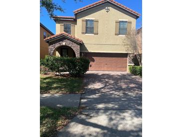 Charming two-story home with brick driveway, archway and beautiful shrubbery at 1812 Leather Fern Dr, Ocoee, FL 34761