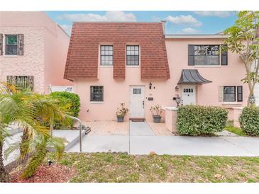 Charming pink townhome featuring a unique red-tiled roof and well-maintained front yard landscaping at 108 Mitchell Pl # 108, Daytona Beach, FL 32118