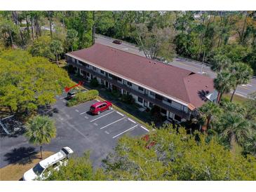 Exterior view of condo building with parking, landscaping, and proximity to the road at 112 Lacosta Ln # 115, Daytona Beach, FL 32114