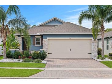 Charming home featuring stone accents, a brick driveway, and beautiful landscaping with palm trees at 214 Caryota Ct, New Smyrna Beach, FL 32168