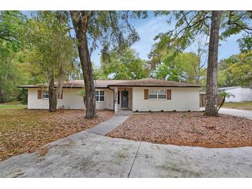 Charming single-story home with white brick, complemented by mature trees and a well-manicured yard at 525 E Wisconsin Ave, Orange City, FL 32763